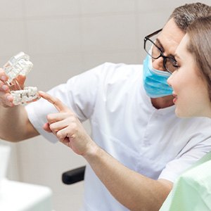 A dentist showing a patient a dental implant model