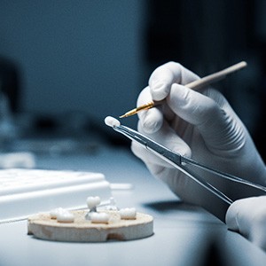 Lab tech’s gloved hands customizing a dental crown