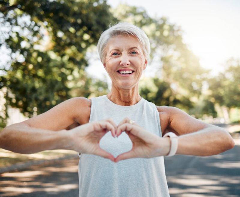 Smiling lady makes shape of heart with her hands