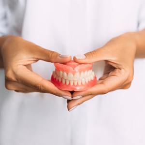 a person holding a model of dentures