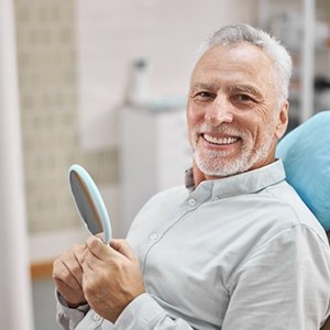 a patient smiling while holding a mirror