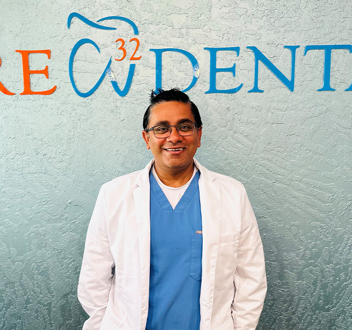 Doctor Krunal Desai smiling in front of sign for Care 32 Dental of Fort Worth