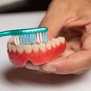 Using toothbrush to clean a full denture